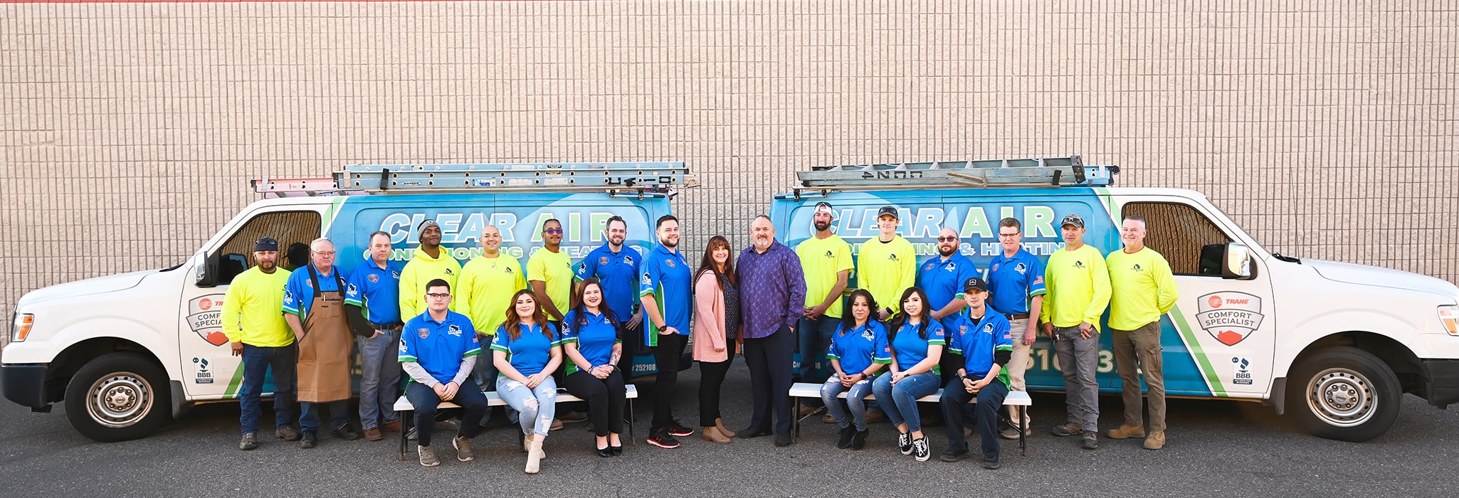 The Clear Air Conditioning & Heating team outside with service trucks.